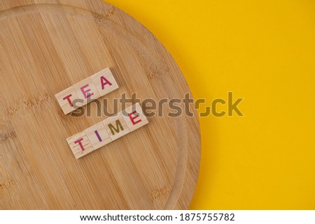 Tea menu concept. Scrabble letter tiles on wooden table. Yellow background.
