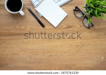 Workplace in office with wooden desk. Top view above of keyboard computer with glasses and coffee cup. Space for modern creative work of designer. Flat lay with copy space. Business-finance concept.