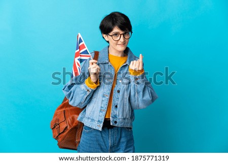 Woman holding an United Kingdom flag over isolated background making money gesture
