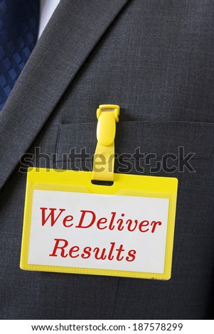 Conceptual image for success in business - name card on a dark suit with a sign saying "We deliver results"