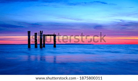 Panoramic Sunset Seascape with Dramatic Clouds and Ruined Silhouette Pilings