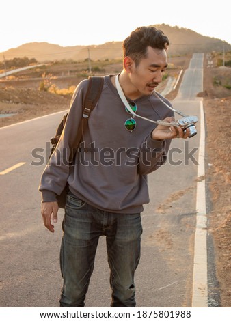 A man Asian and Thai nationality carrying a backpack and taking pictures  at Lamapng, Thailand