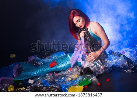 Ocean plastic pollution. Cute mermaid swimming in water with plastic garbage. Stop plastic pollution. Fairy tale and reality concept.