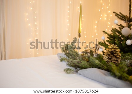 New Year's table, decorations, green spruce on a white table, in the background of the golden photo