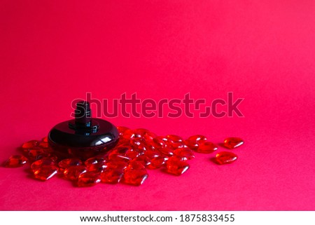A bottle of perfume on a red table among glass hearts. A gift for Valentine's Day to your beloved, dating. Copy space