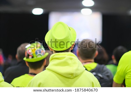Rear view of people wearing festival green hat and clothes attending holiday event. Festival, Christmas, holiday, new year, live event and presentation background.