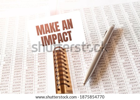 Text MAKE AN IMPACT on paper card,pen, financial documentation on table - business, banking, finance and investment concept. close up of stock market chart.