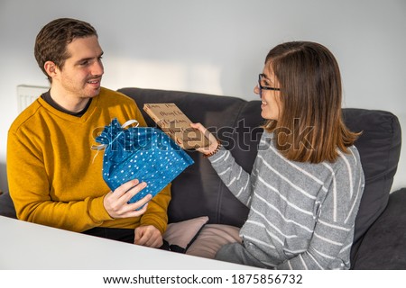 Photo of a young and attractive couple at home exchanging Christmas presents and saying thank you to each other. Joy, love, relationship