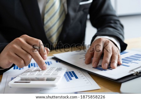 Close-up of businessmen or accountants holding a pen and pressing on the calculator to calculate business information, Finance documents, business ideas.