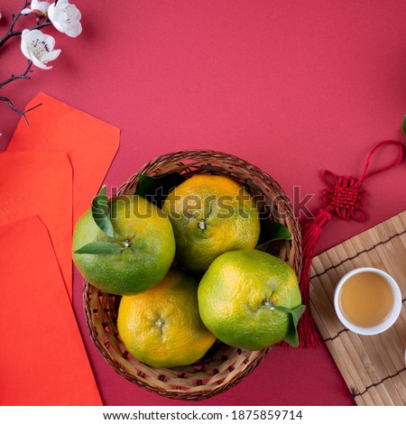 Top view of fresh ripe tangerine mandarin orange with fresh leaves on red table background for Chinese lunar new year fruit concept, the Chinese word means spring.