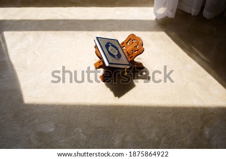 Quran holy book with silver embossing at wooden stand in room with sun light, muslim pray, islamic home  Royalty-Free Stock Photo #1875864922