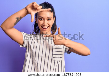 Young woman wearing casual clothes smiling making frame with hands and fingers with happy face. creativity and photography concept. 