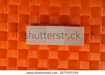 Three wooden cubes on orange background with copyspace
