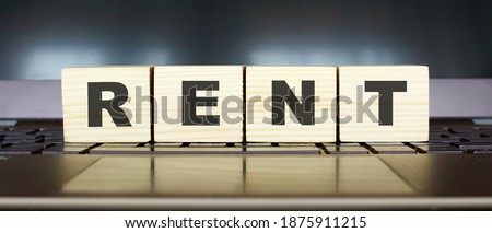 Word RENT. Wooden cubes with letters isolated on a laptop keyboard. Business Concept.