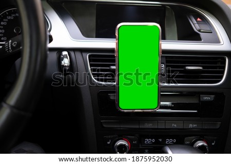 smartphone green screen attached to the ventilation grille inside the car Royalty-Free Stock Photo #1875952030