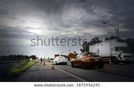 Blurry cars running through temporary condition road warning sign with stormy cloud,dark and dramatic scene with low-speed shutter.