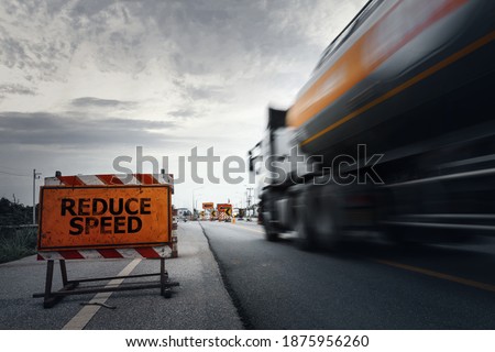 Reduce speed road sign on a countryside road with blurry speed truck,dark and dramatic scene with low-speed shutter.