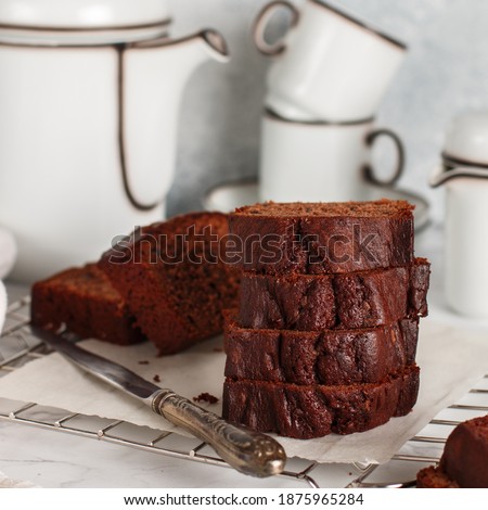 Sliced homemade chocolate pound cake loaf. Delicious dessert. A treat for tea or coffee. Breakfast on a marble table against a gray concrete wall. Selective focus, square picture