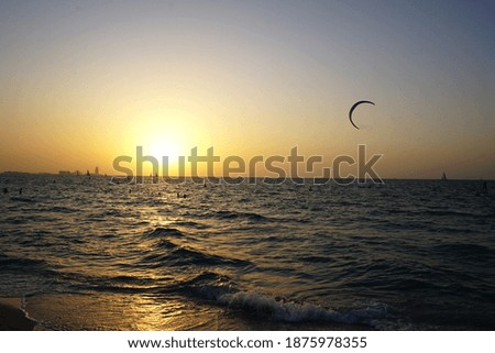 Kite-surfing and yachts on orange sunset background. Travel concept.