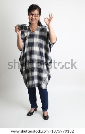 The elder Asian woman standing on the white background.