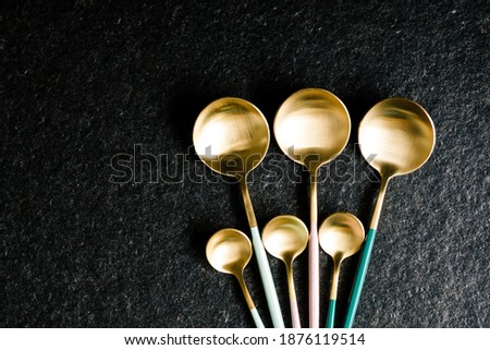 set of stylish colored spoons on a black background. Modern kitchen. Restaurant food. Copy Space
