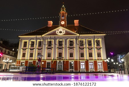 Tartu town halls main square. Ice skating arena built there for the winter period. Colorful led lights as decorations. Empty skating field -just cleaned-wet.Old historical building. Amazing reflection
