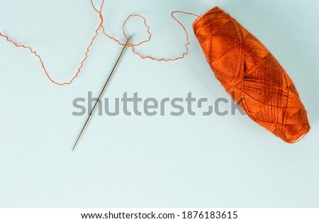 Textile industry, thread and needle, blue background, place for advertising or text