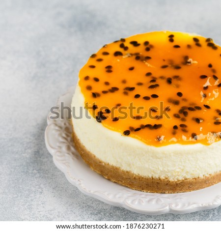 Passion fruit cheesecake on a white plate on a gray concrete background. Delicious homemade cake. Selective focus, copy space, square picture