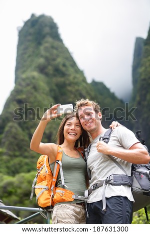 Couple taking selfie self portrait hiking on Hawaii in outdoor activity. Woman and man hiker taking photo with smart phone camera. Healthy lifestyle from Iao Valley State Park, Wailuku, Maui, USA.
