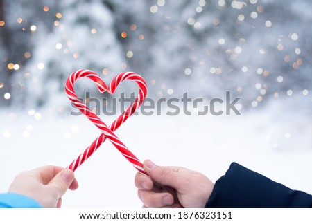 Two lollipops in the shape of a red and white heart on a blurry background of bokeh lights.love on valentine's day. The Christmas sweets