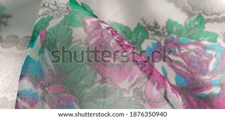 Translucent slightly shiny fabric with pink-blue-green floral print and gray border, in folds (texture).