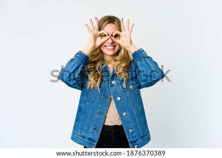 Young caucasian blonde woman excited keeping ok gesture on eye.