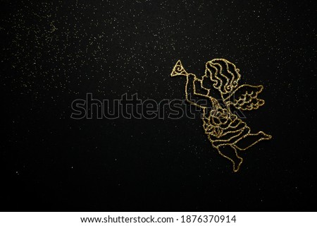 New Year's angel with a trumpet on a black background. A festive gift for Christmas. Golden toy for the Christmas tree. Beautiful background for your desktop. High quality photo