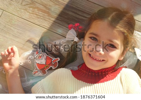 Little girl on Christmas background. Baby playing with Santa Claus. Child dreams. New Year gift. Good Mood During The Winter Holidays. Positive emotions. Magic time for fulfilling your wishes. Happy