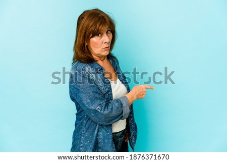 Senior caucasian woman isolated smiling and pointing aside, showing something at blank space.