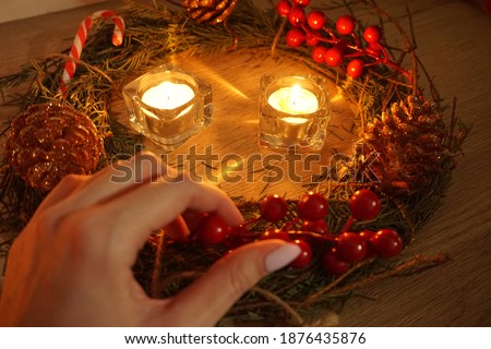 Dark Christmas decoration. Wreath with candles and gift on the wooden table.