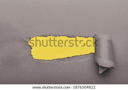 Gray torn paper with yellow paper as background. Empty place for text in paper hole.