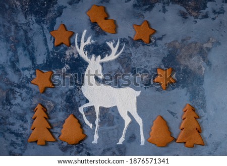 Silhouette of a deer made from flour and christmas cookies on dark background