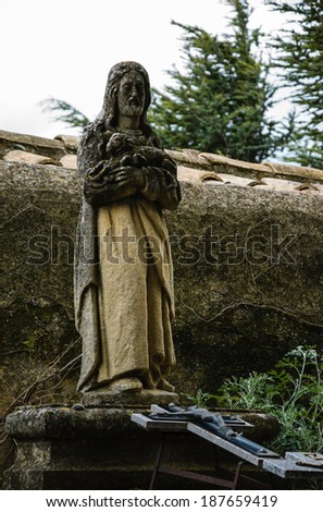 Tombstone with the Christ holding the lamb statue and the crucifix at beneath. Old cemetery in Les Baux-de-Provence (Provence, France).