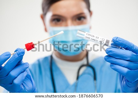 Female UK GP physician wearing personal protective equipment performing Coronavirus COVID-19 rt-PCR test,patient nasal NP oral OP swab sample specimen collection process,viral DNA diagnostic procedure Royalty-Free Stock Photo #1876606570