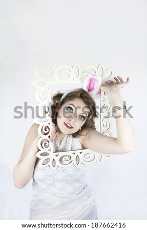 Beautiful young woman wearing rabbit ears and holding Easter basket with sequin Easter eggs coming out of picture frame.