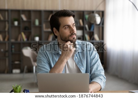 Pensive young Caucasian woman work on laptop in home office look in window distance thinking pondering. Thoughtful serious woman distracted from computer job make decision or plan at workplace. Royalty-Free Stock Photo #1876744843