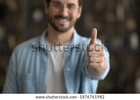 Crop close up blurred view of happy male client or customer show thumb up recommend good quality service or company. Smiling man feel satisfied pleased give recommendation. Review concept. Royalty-Free Stock Photo #1876761982