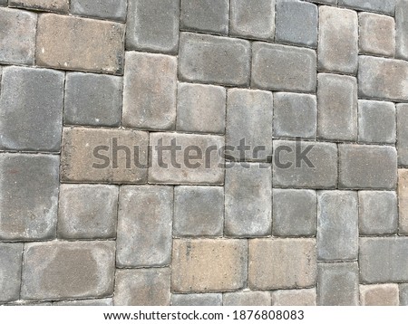 Brick paver background in a random pattern with brown, grey, and tan color tones.