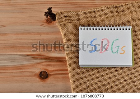 A small sketchbook with the word SDGs written on it was on the cedar table with hemp bag.