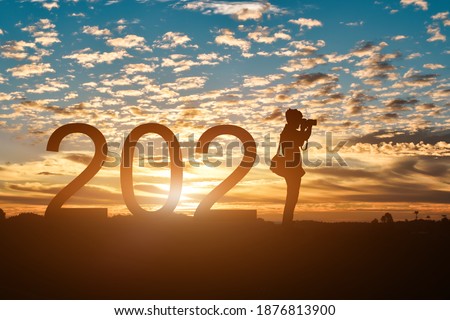 Silhouette of photographer taking photos in 2021 years at sunrise or sunset background, with copy space. Idea for happy new year 2021.