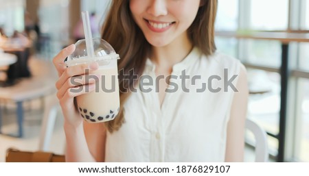 close up of asian young woman look and drink bubble milk tea at the restaurant