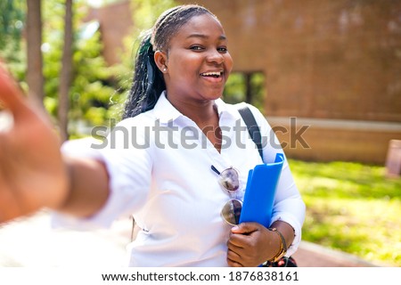 Beautiful smiling young african woman wearing white t-shirt and holding a copybook
