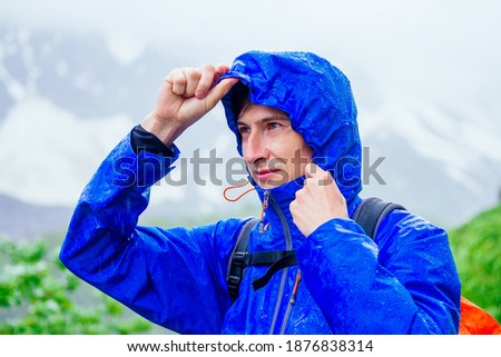 man in blue jacket with rain in mountains