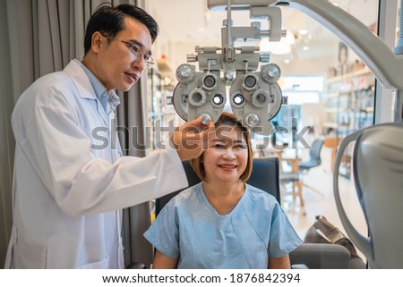 optometrist using phoropter to check eyesight value for client eyeglasses in optical store